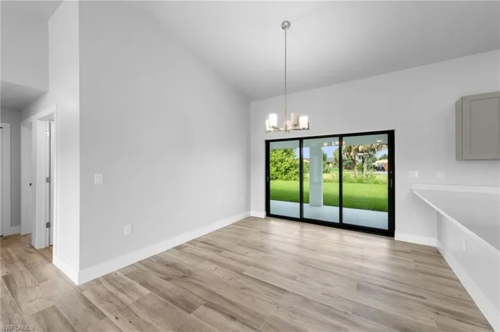 Interior space featuring wood-finish flooring, vaulted ceilings, and a contemporary chandelier