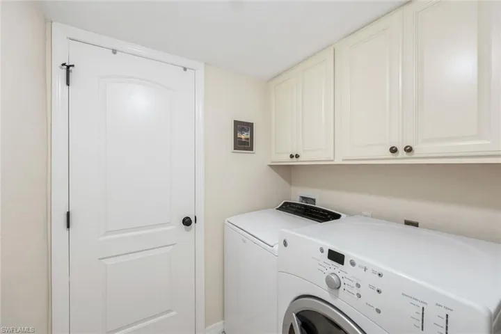 Laundry area featuring upper cabinetry with bronze hardware, a light-colored countertop, and a white paneled door with black hardware