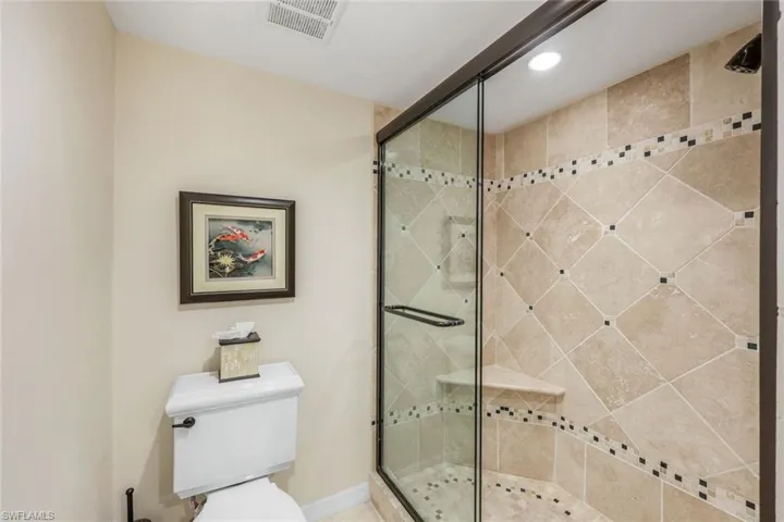 Walk-in shower with clear glass enclosure and dark bronze framing