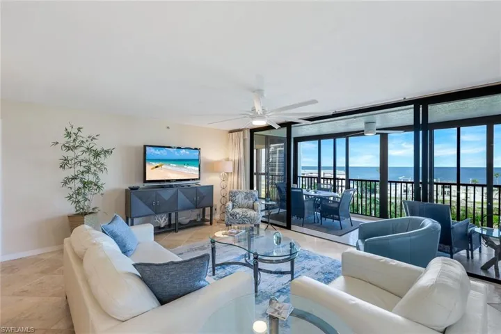 Spacious living area featuring expansive glass sliding doors opening to a balcony with ocean scenery