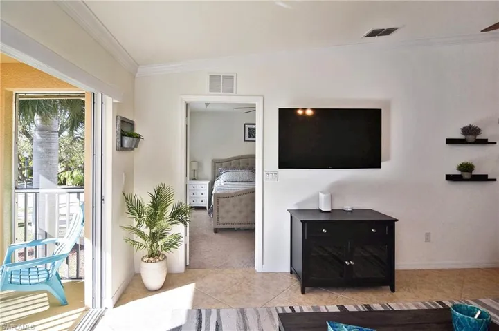 Living room featuring ornamental molding, light tile patterned floors, and light carpet