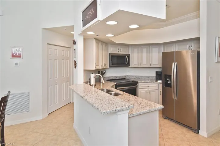 Kitchen featuring stainless steel appliances, light stone countertops, light tile patterned floors, recessed lighting, and a peninsula