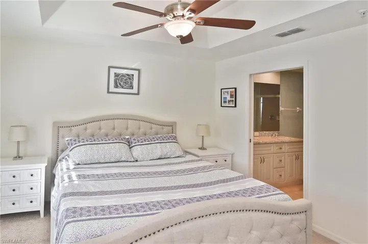 Bedroom featuring light carpet, connected bathroom, and a ceiling fan