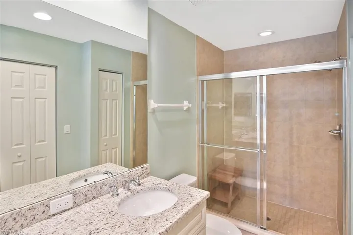 Bathroom featuring a closet, vanity, a shower stall, and recessed lighting