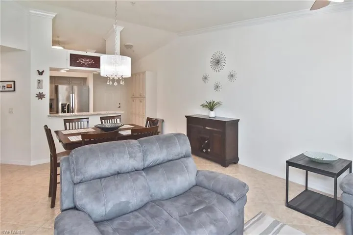 Living room featuring lofted ceiling, light tile patterned flooring, a chandelier, and ornamental molding