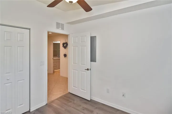 Unfurnished bedroom featuring a closet, ceiling fan, light wood finished floors, and electric panel