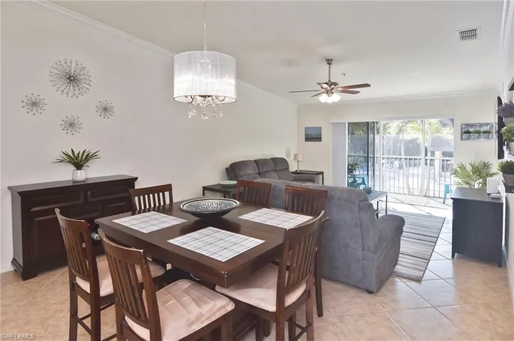 Dining room featuring ceiling fan, ornamental molding, light tile patterned floors, and a chandelier