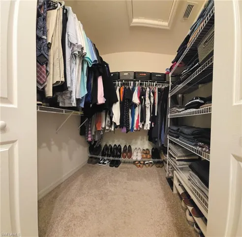 Walk in closet featuring light carpet and attic access