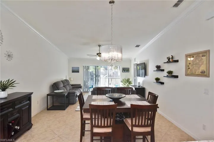 Dining room with a chandelier, ornamental molding, ceiling fan, and light tile patterned flooring