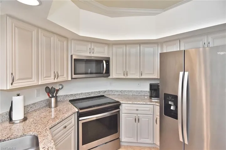 Kitchen featuring stainless steel appliances, light stone countertops, and white cabinets