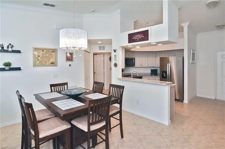 Dining room with ornamental molding, a chandelier, and light tile patterned flooring