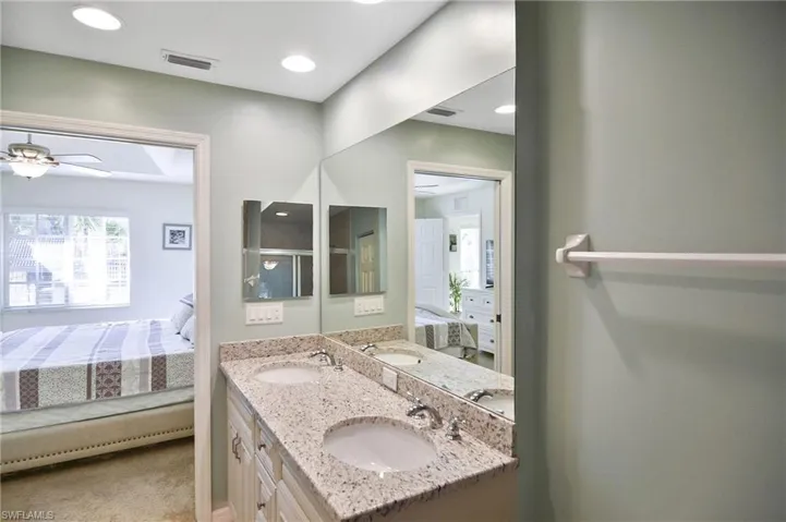 Bathroom with connected bathroom, double vanity, ceiling fan, and light carpet