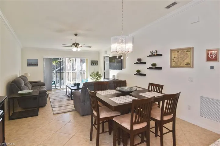 Dining space with a ceiling fan, crown molding, a chandelier, and light tile patterned floors