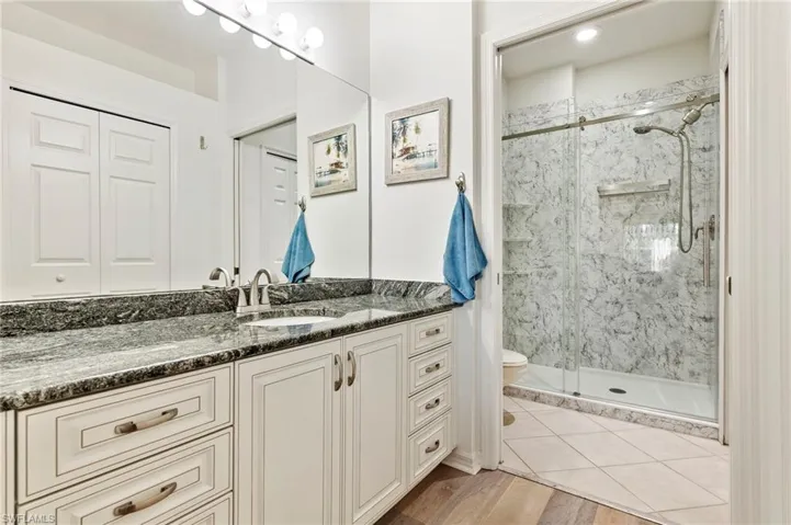 Bathroom with vanity, a marble finish shower, and light wood-style flooring