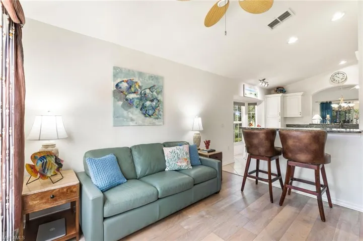 Living room with recessed lighting, light wood finished floors, a ceiling fan, and a chandelier