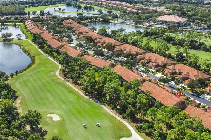 Aerial view of property's location featuring a golf course, nearby suburban area, and a nearby body of water