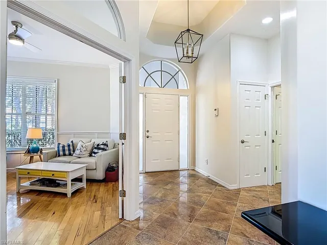 Foyer entrance with a high ceiling, suspended lighting, and wood finished floors