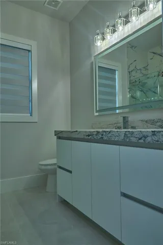 Bathroom featuring vanity, tile patterned flooring, and toilet