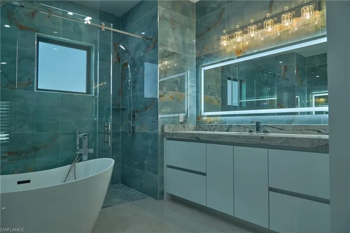 Bathroom featuring shower with separate bathtub, vanity, tile walls, and tile patterned floors