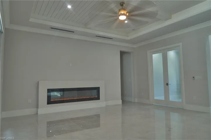 Unfurnished living room with tile patterned floors, french doors, and a raised ceiling