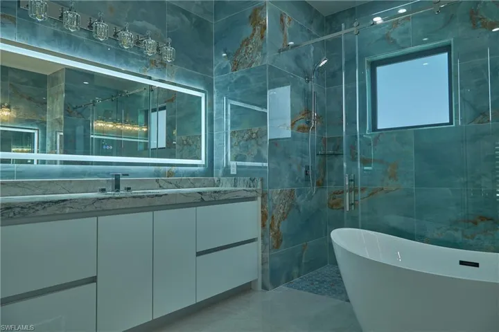 Bathroom featuring tile patterned flooring, tile walls, plus walk in shower, and vanity