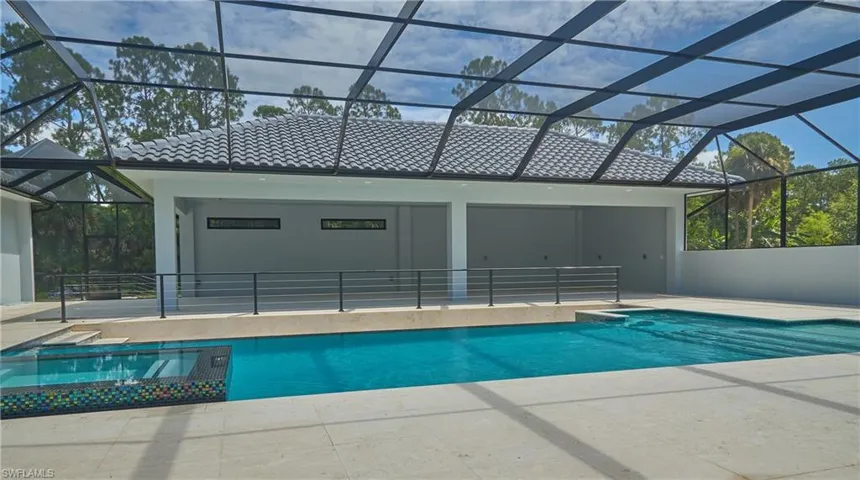 View of pool with a patio area and glass enclosure