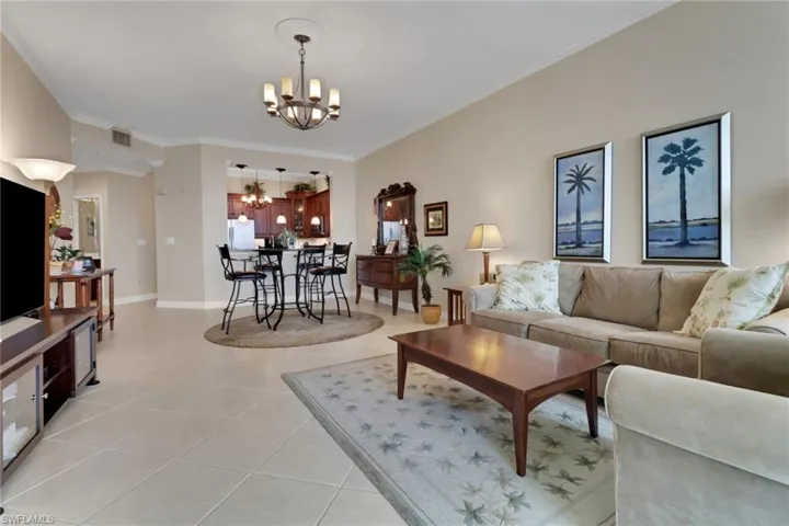 Living area with crown molding, a chandelier, and light tile patterned flooring