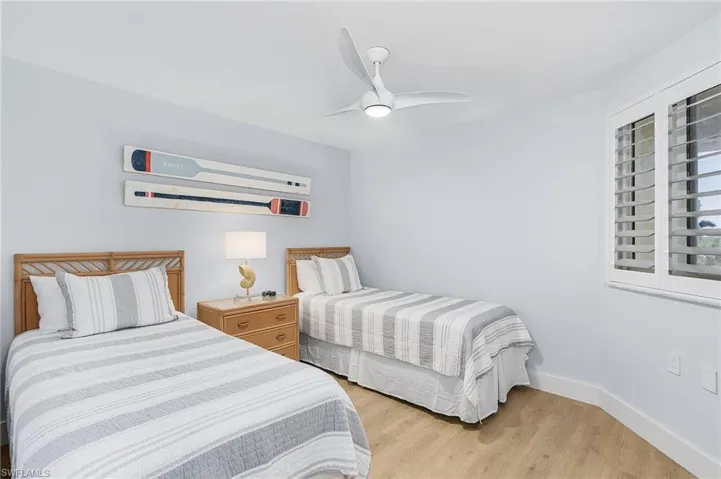 Bedroom with light hardwood / wood-style floors, a wall mounted AC, and ceiling fan