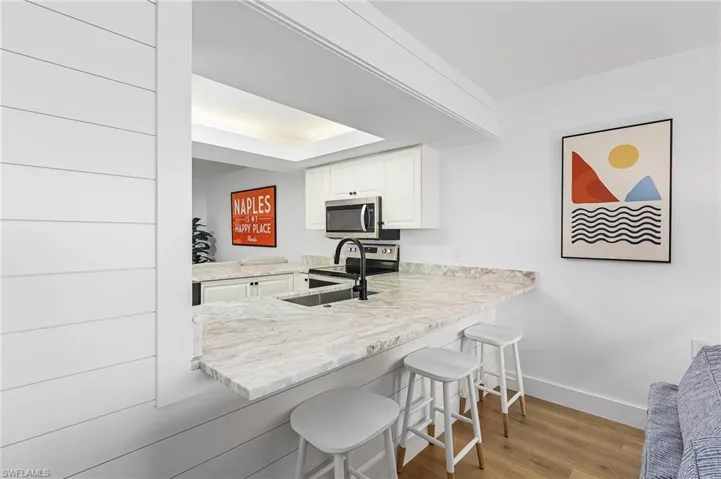 Kitchen featuring white cabinets, light wood-type flooring, a breakfast bar area, appliances with stainless steel finishes, and kitchen peninsula