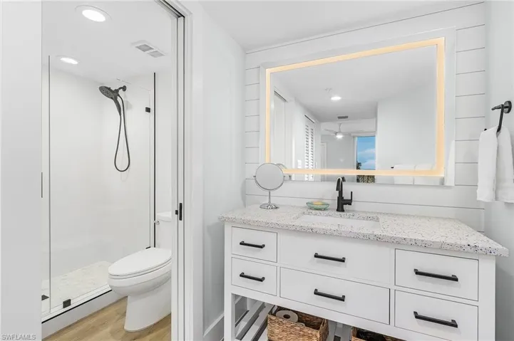 Bathroom with walk in shower, wood-type flooring, toilet, and vanity