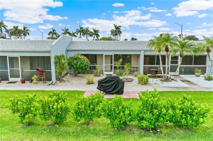 Back of property featuring a sunroom, a yard, a shingled roof, and stucco siding