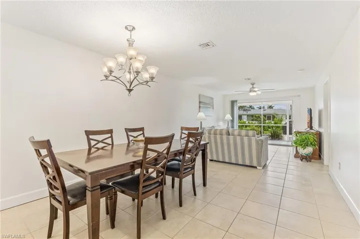 Dining area with light tile patterned floors, a chandelier, ceiling fan, and a textured ceiling
