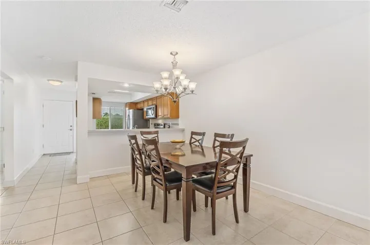 Dining room with a chandelier, light tile patterned floors, and a textured ceiling