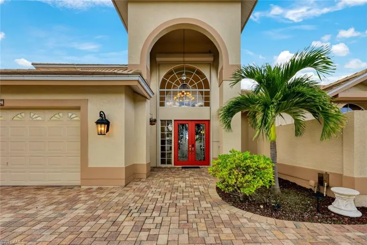 Stucco exterior with an arched entryway and a prominent red double-door entry
