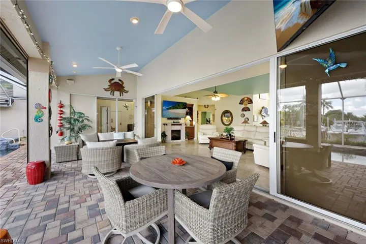 xpansive outdoor living area featuring a paved patio and a vaulted ceiling with multiple ceiling fans