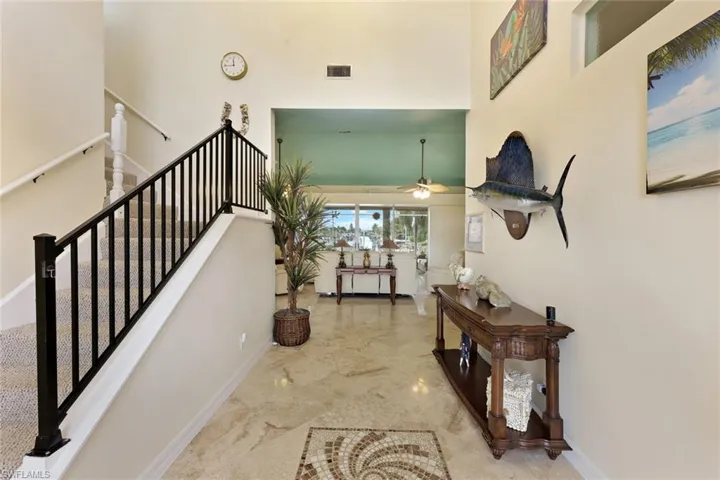 Two-story entryway with a wrought iron staircase, tile flooring, and a decorative mosaic inlay