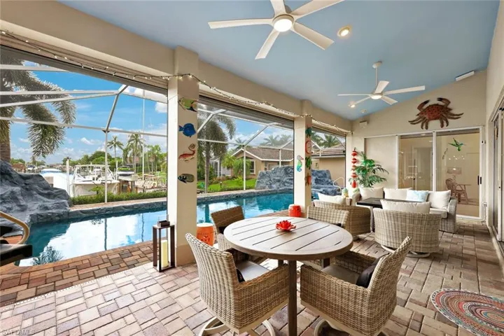 Screened lanai with brick paver flooring, multiple ceiling fans, and direct access to a swimming pool & spa.