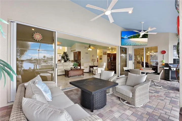 Outdoor living area featuring a paved patio and a vaulted ceiling with multiple ceiling fans