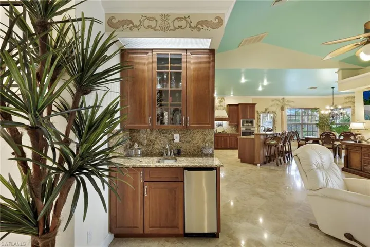 Built-in wet bar with wood cabinetry, stone countertops, and integrated beverage cooler