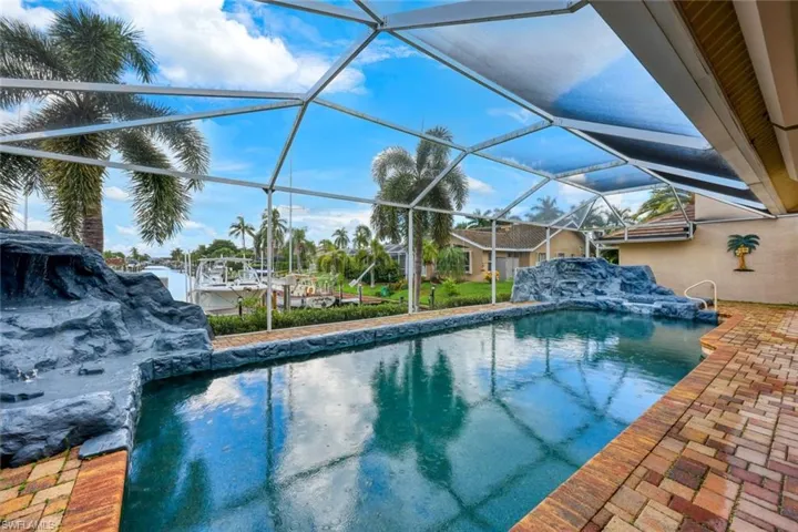 Screened outdoor pool and spa with rock-finish water falls and a brick paver deck