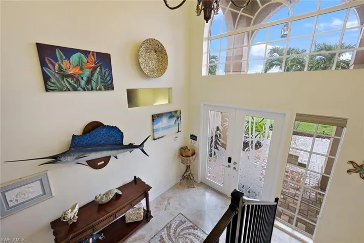 Expansive two-story entry with dual entry doors, transom window, and marble tile flooring with a mosaic inlay