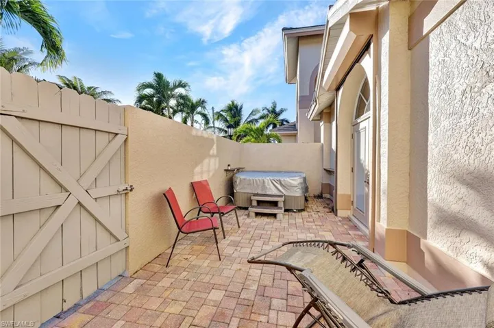 Private patio off the Primary Bedroom featuring paver flooring, stucco privacy wall, above ground spa, wood-slat gate