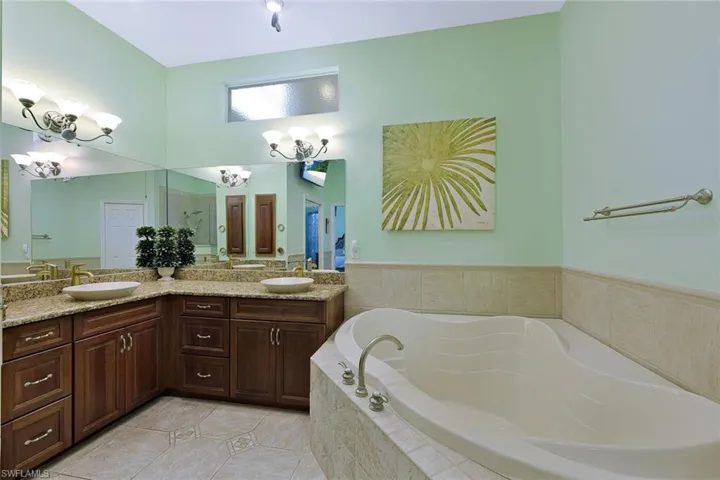 Dual vessel sinks, granite countertops, wood-finish cabinetry, built-in soaking tub, and Walk-in Shower.