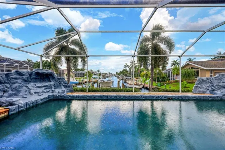 Screened enclosure encompassing a swimming pool with a rock-finish waterfall feature