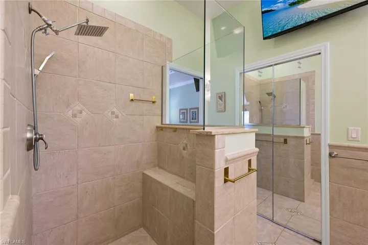 Tiled shower enclosure featuring a fixed shower head and handheld sprayer