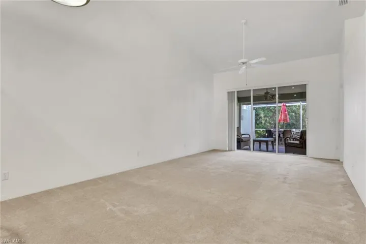 Carpeted spare room featuring ceiling fan and vaulted ceiling