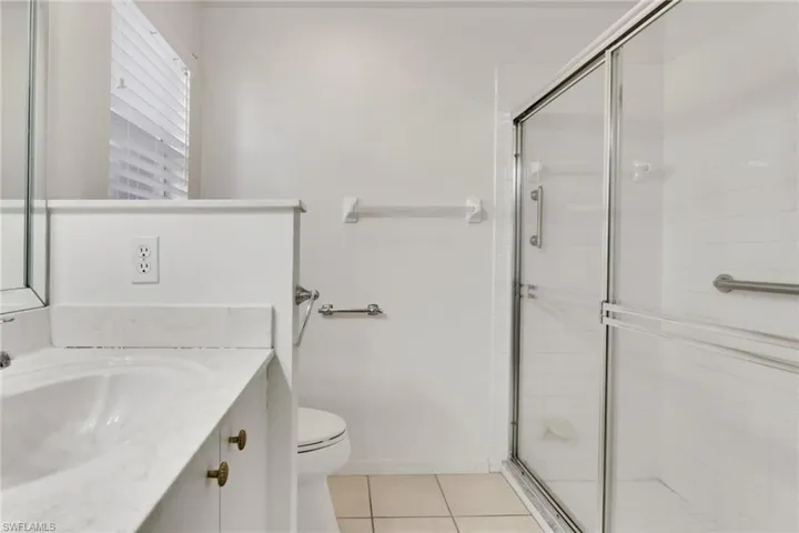 Bathroom featuring light tile patterned floors, vanity, and a stall shower