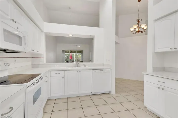 Kitchen featuring white appliances, white cabinetry, light countertops, and ceiling fan