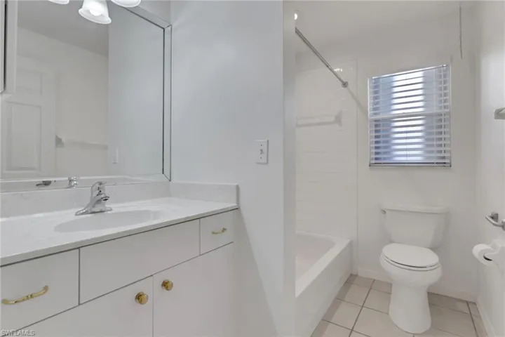 Full bathroom featuring vanity, light tile patterned flooring, and washtub / shower combination