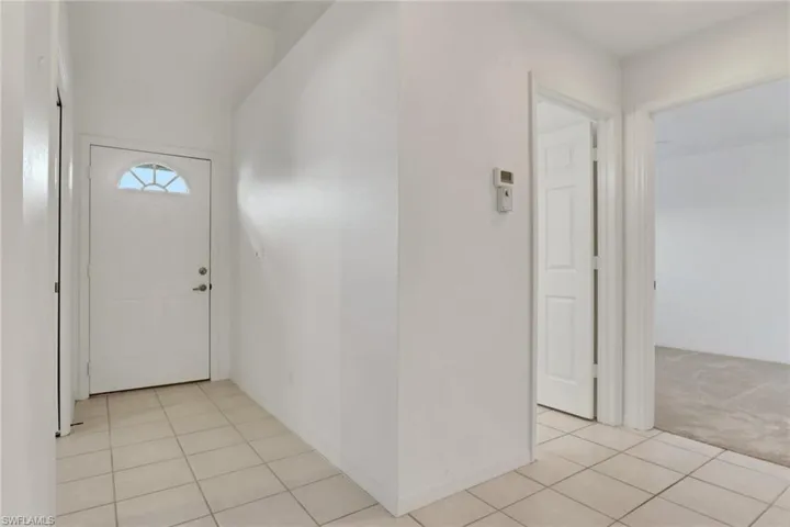 Entrance foyer with light tile patterned floors and light carpet